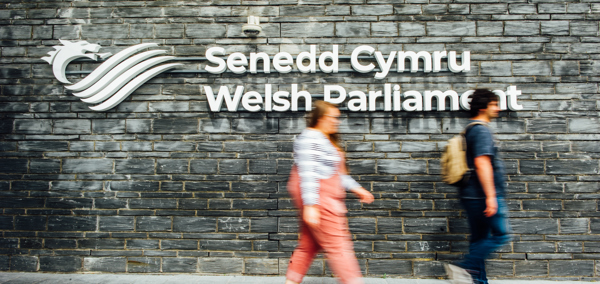 People walking past the Senedd signage